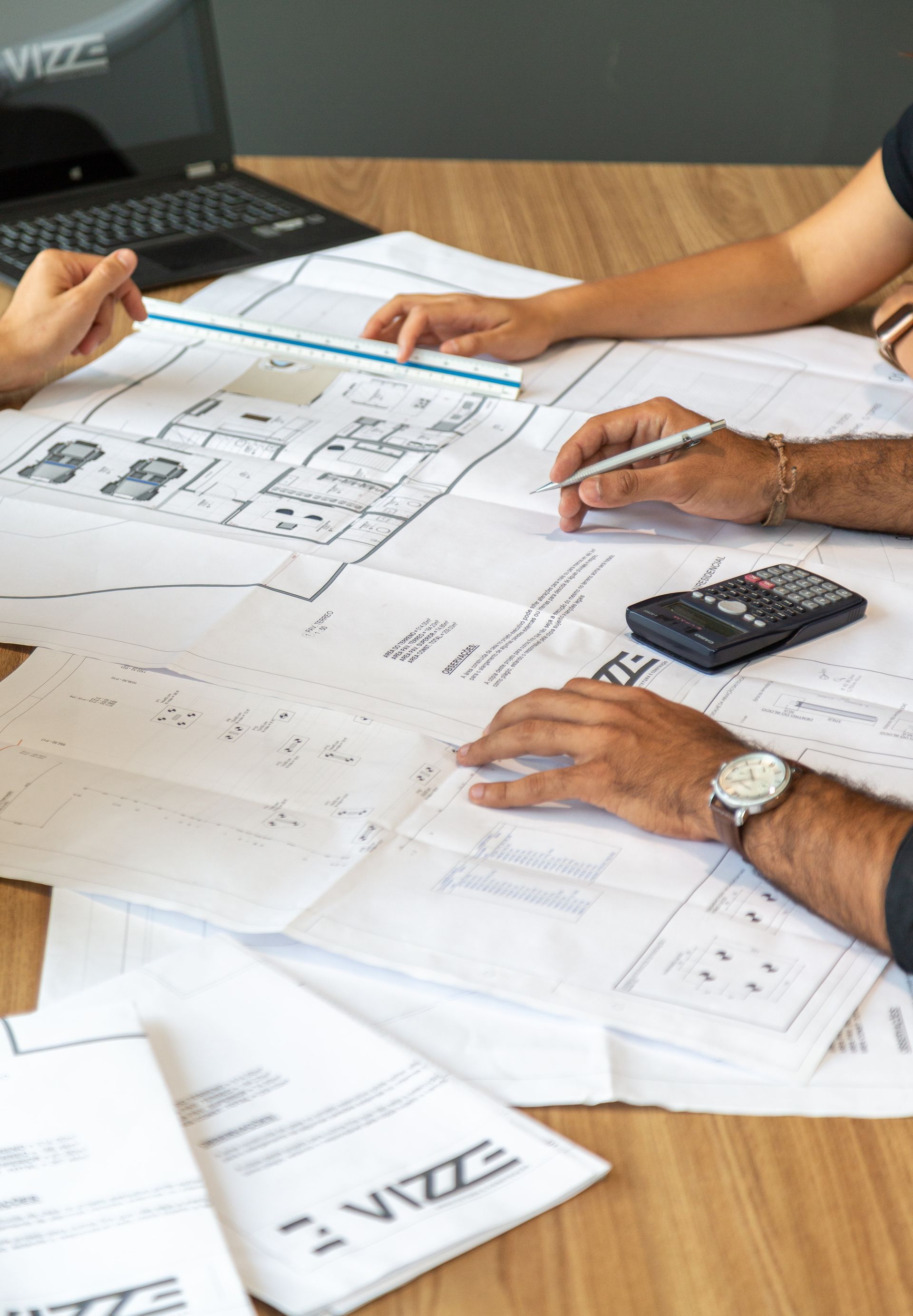 A group of people are sitting around a table looking at blueprints.