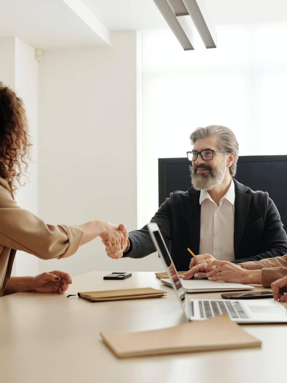 A man and a woman are shaking hands while sitting at a table.