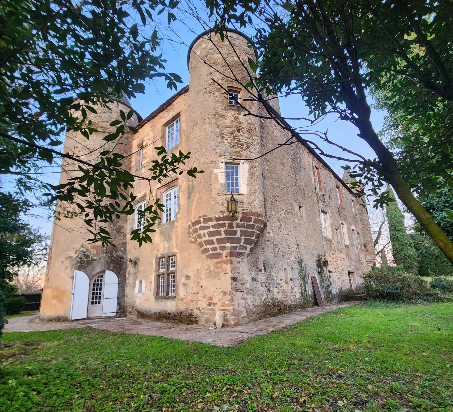 Un vieux château en pierre, avec deux tourelles et des portes cintrées blanches