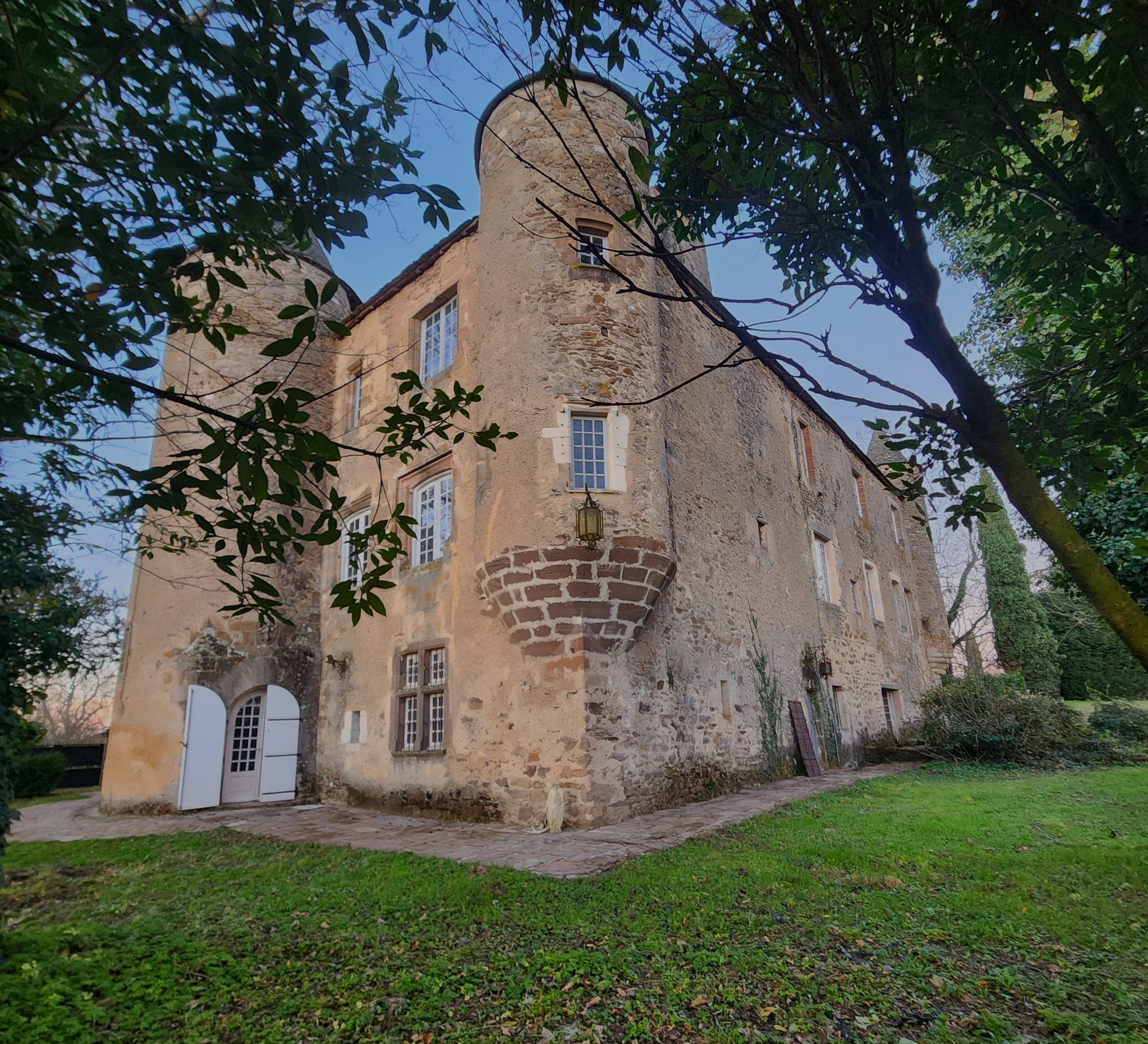 Un château historique en pierre beige, avec deux tours arrondies et des portes blanches