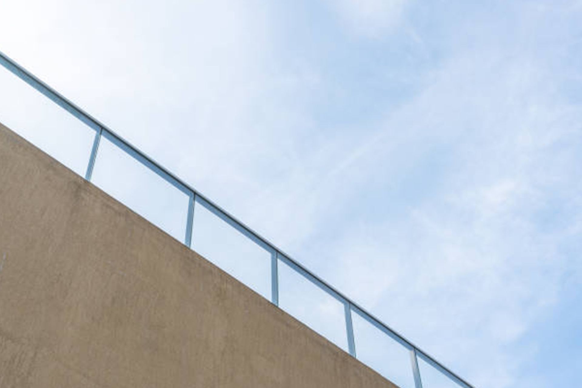 A building with a railing on the side of it and a blue sky in the background.
