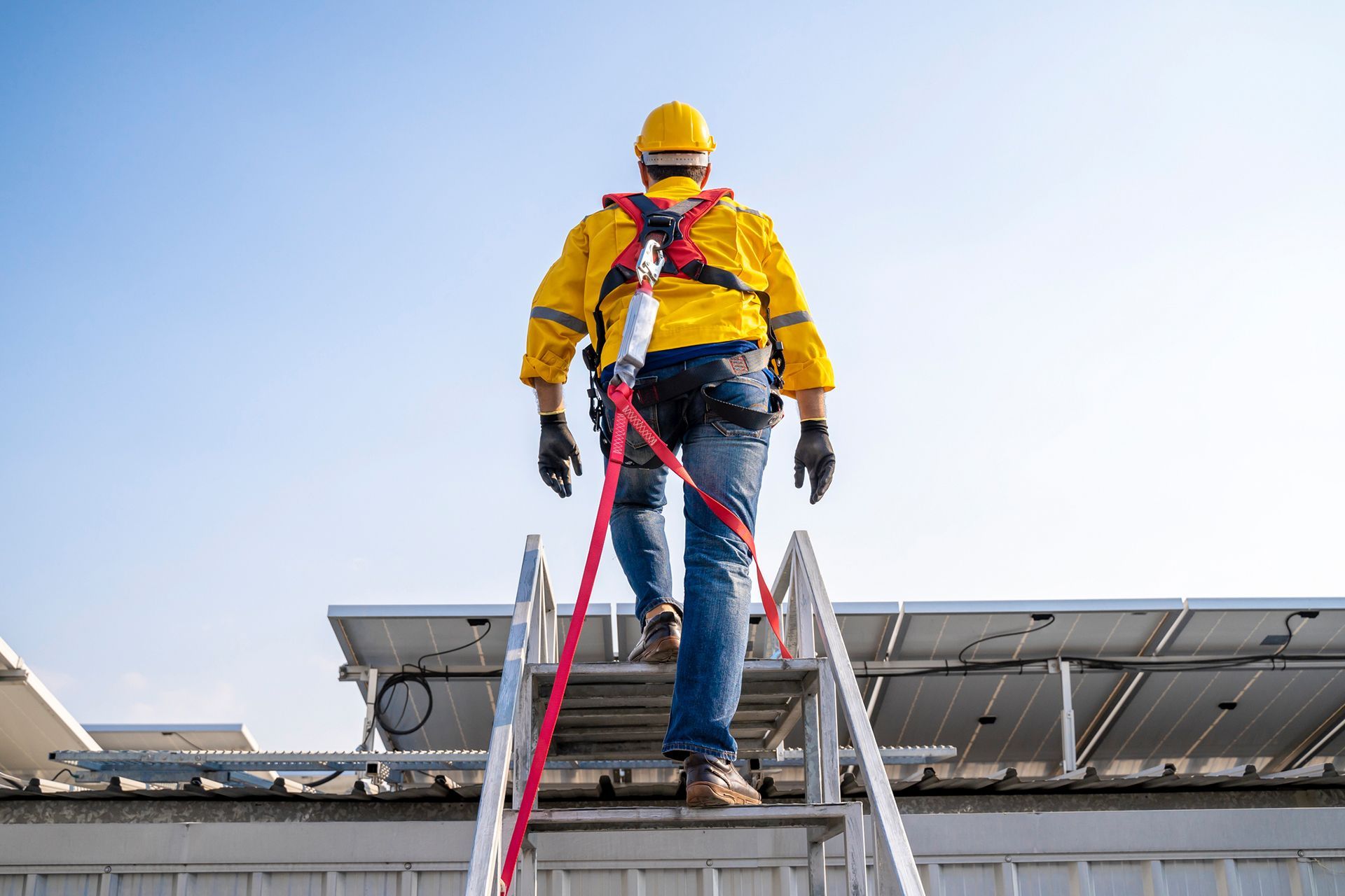 A man is walking up a ladder on top of a building.