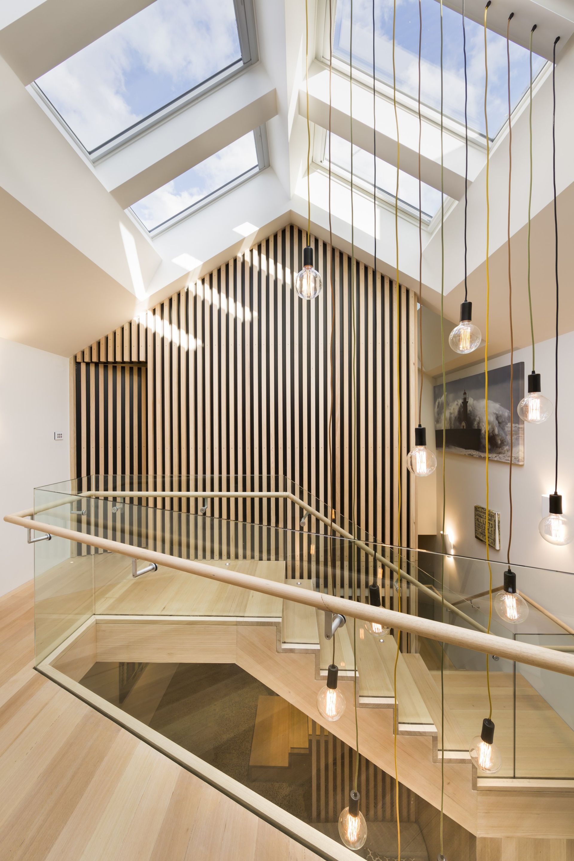 Modern staircase with skylights, wooden accents, and pendant lights.