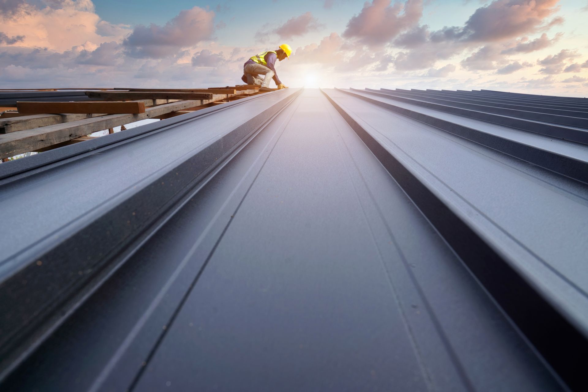 Workers install metal sheet roofs using roofing tools and electric drills.