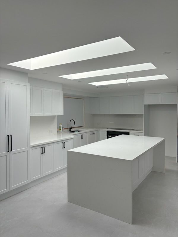White kitchen with large island, cabinets, and skylights.