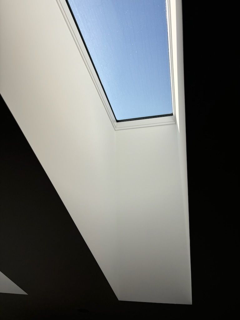 Skylight framed by white walls, looking up at the blue sky.