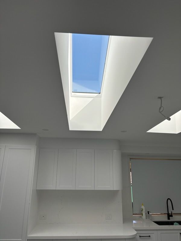 Kitchen ceiling with a rectangular skylight; white cabinets and walls.