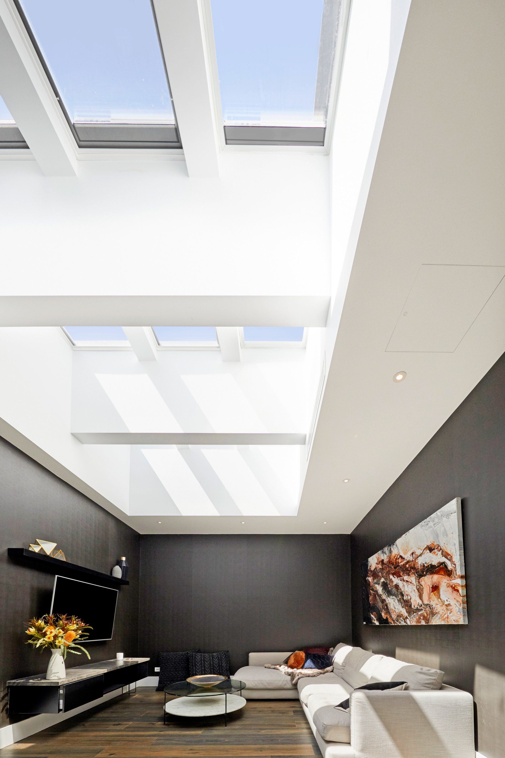 Living room with a skylight, dark grey walls, and a sectional sofa.