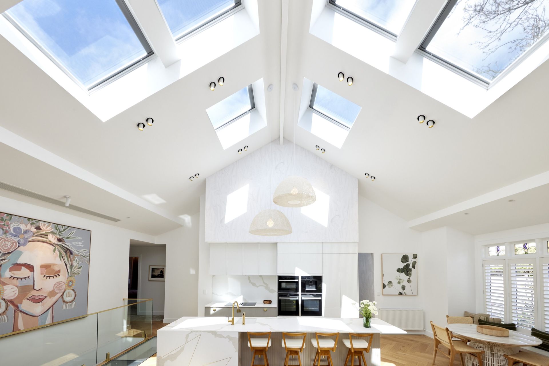 Bright white kitchen with skylights, island, and neutral decor; a light and airy space.