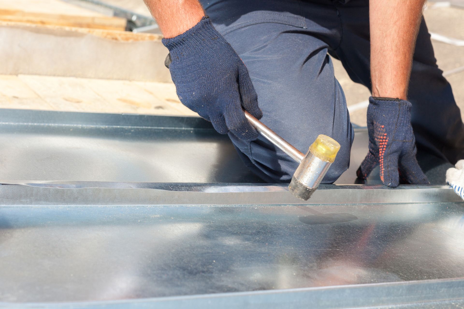 A Roofer is finishing folding a metal sheet provided by a roofing materials company.