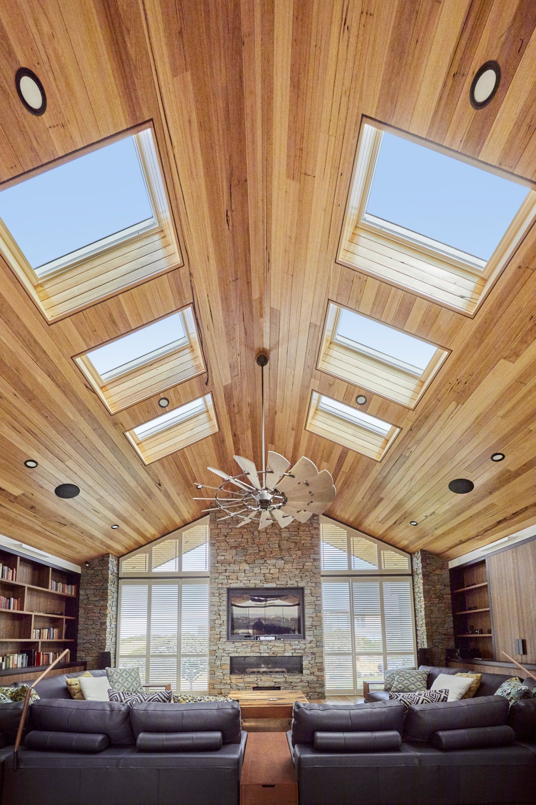 Wooden vaulted ceiling with skylights and a fireplace in a modern living room.
