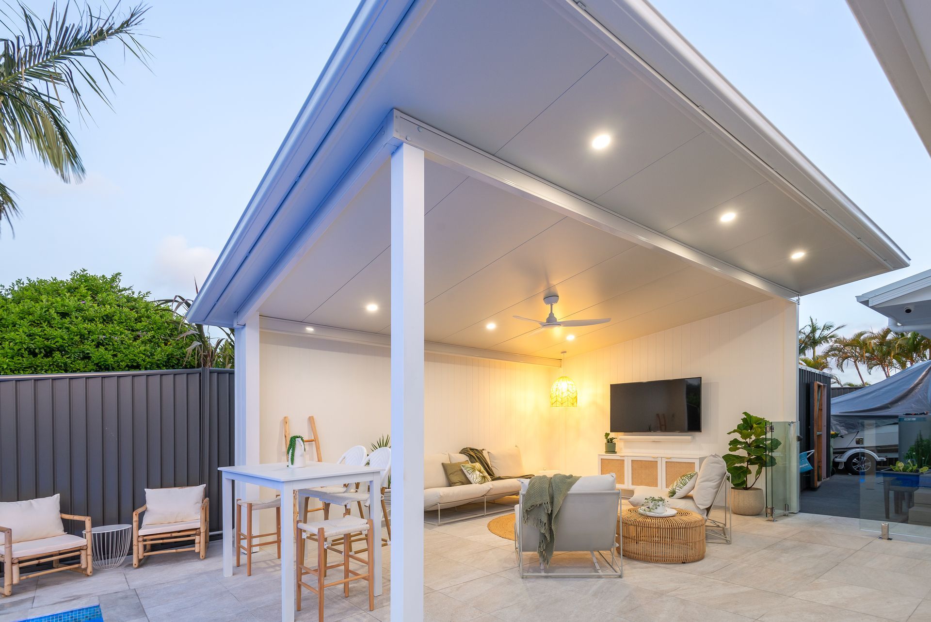 Outdoor living space with white columns, ceiling, and furniture.