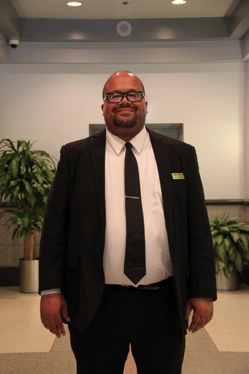 A man in a suit and tie is standing in front of a plant