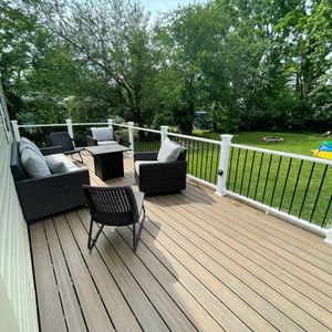 Deck with outdoor furniture overlooking a green yard, trees, and blue sky.