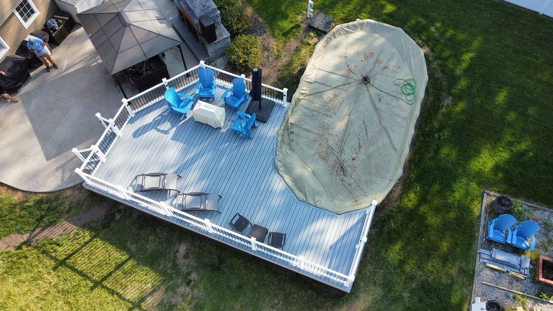 Overhead view of a white deck with blue chairs, covered umbrella, and green lawn.