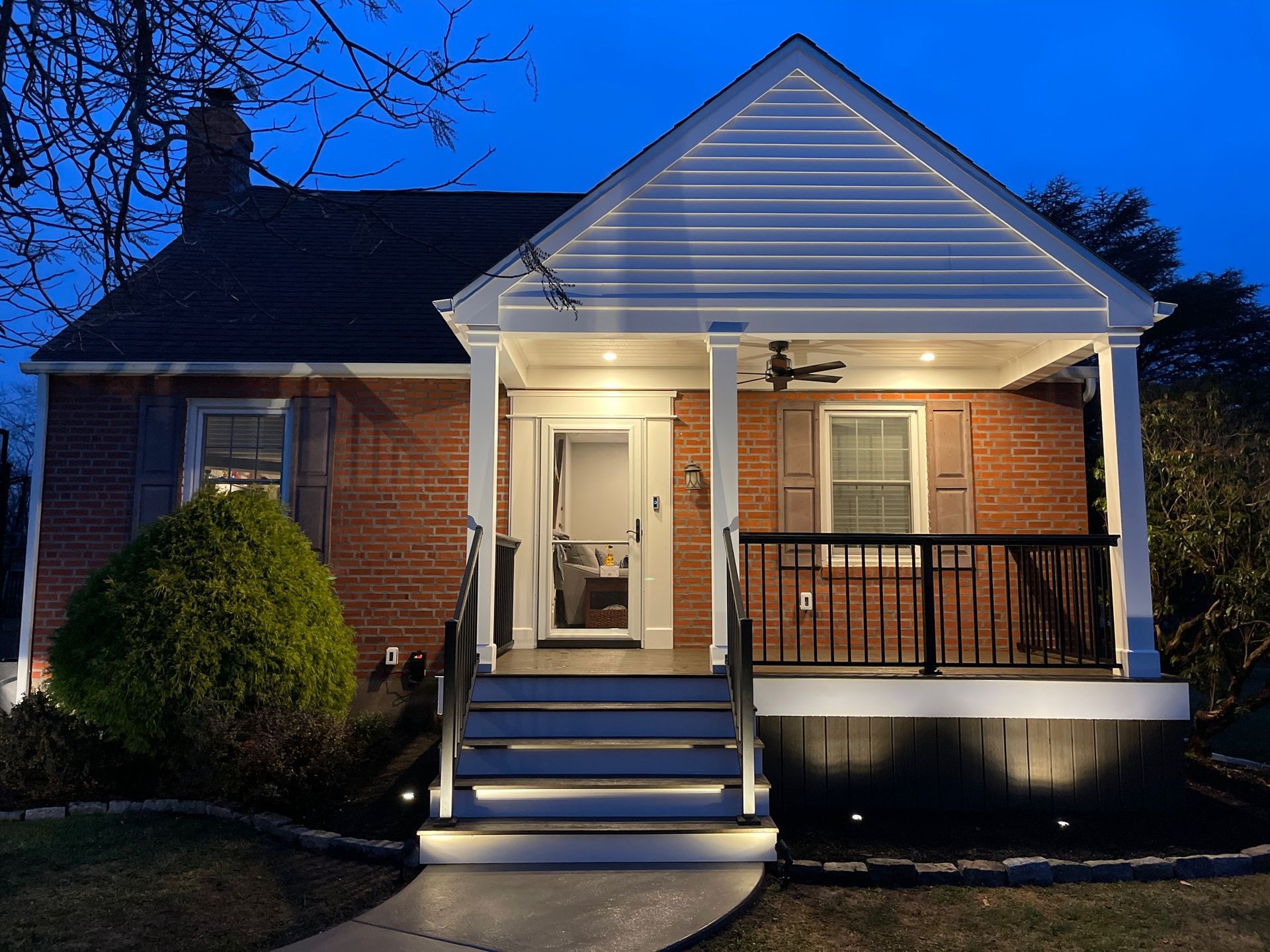Brick house at night with porch and steps lit by small lights.