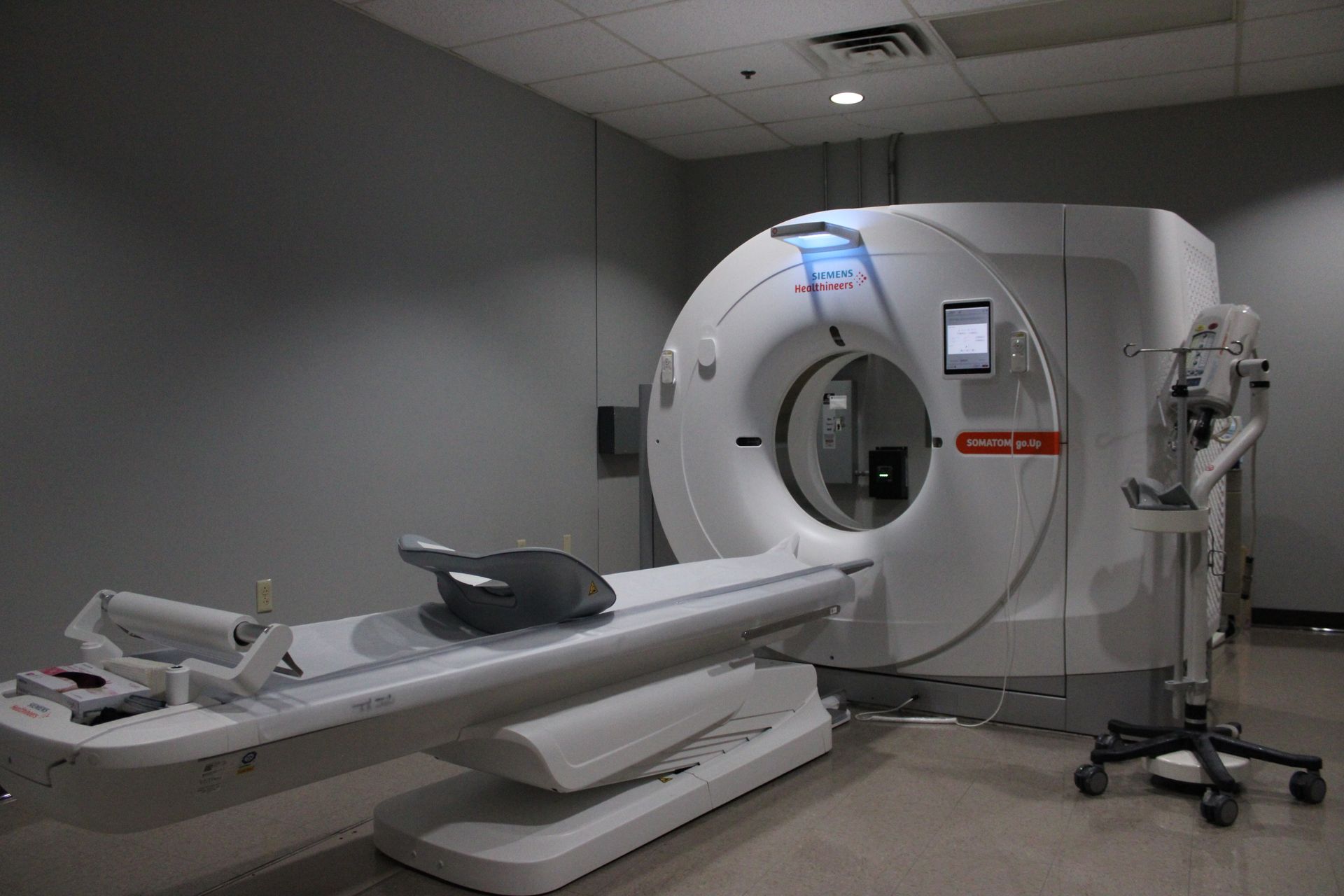 CT scanner in a medical room, showing the machine's gantry and patient table.