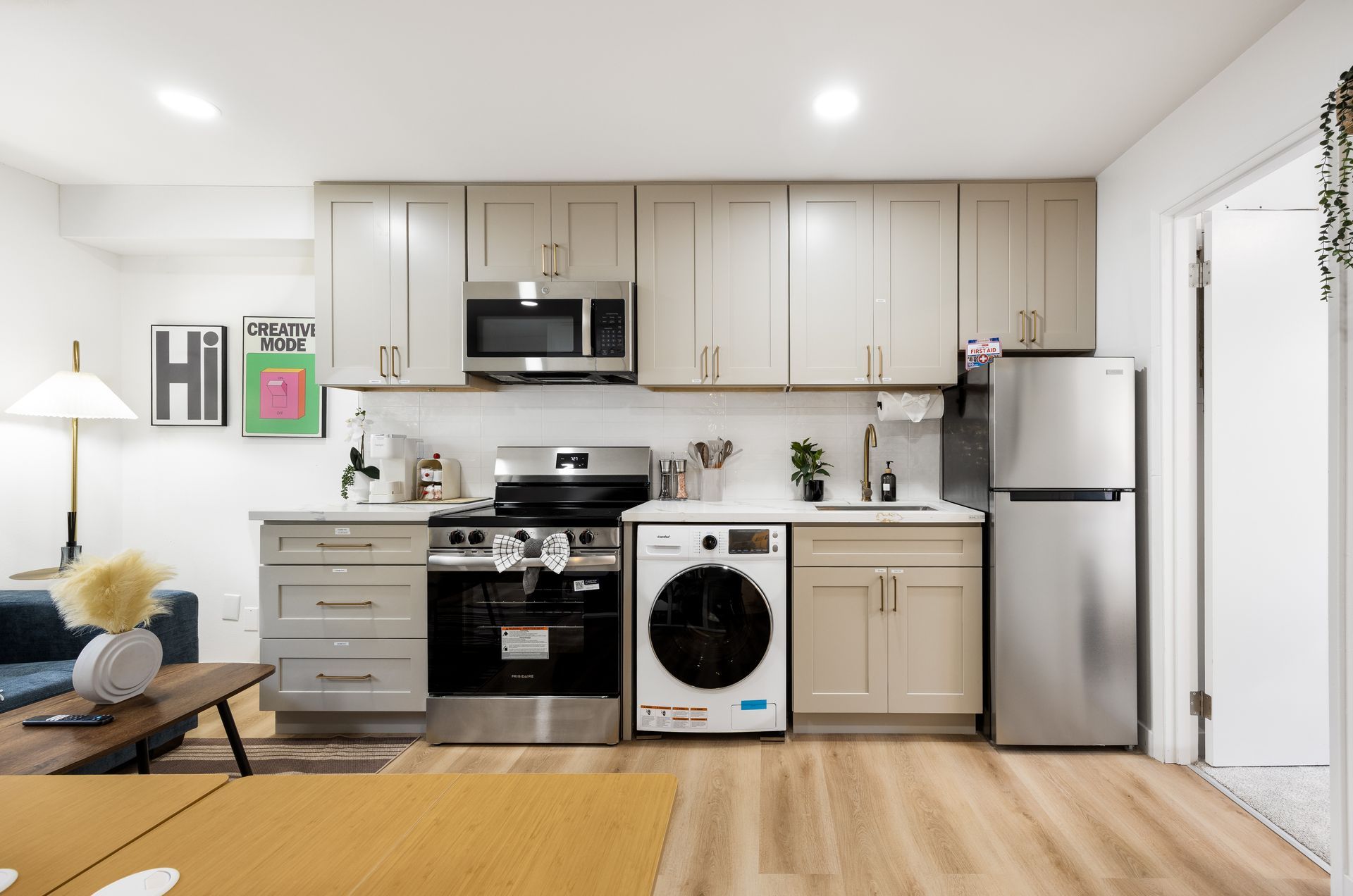 Modern kitchen with white cabinets, stainless appliances, black stove, and a washer under the counter