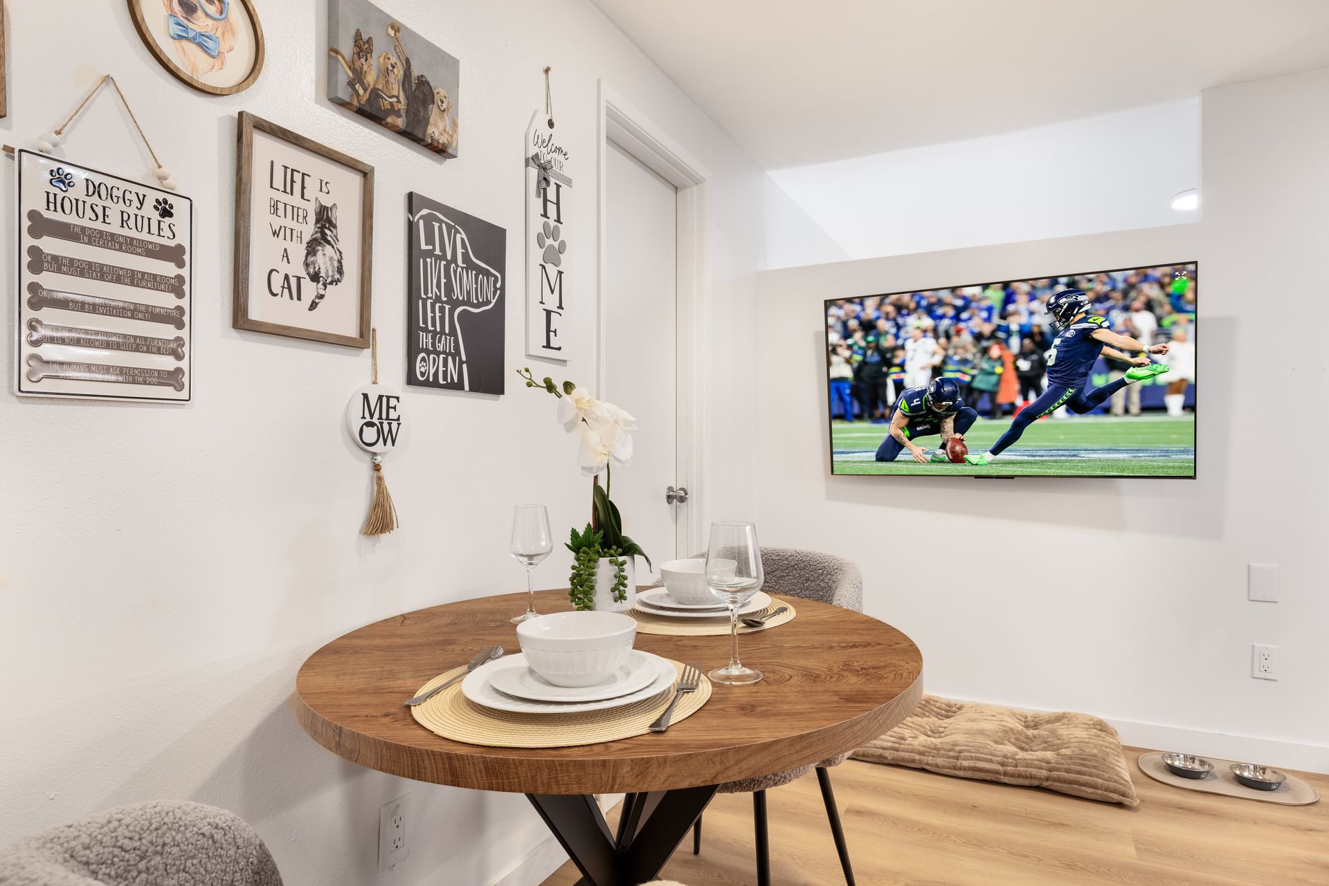 Cozy dining nook with wall art, round table, and a TV showing a soccer game