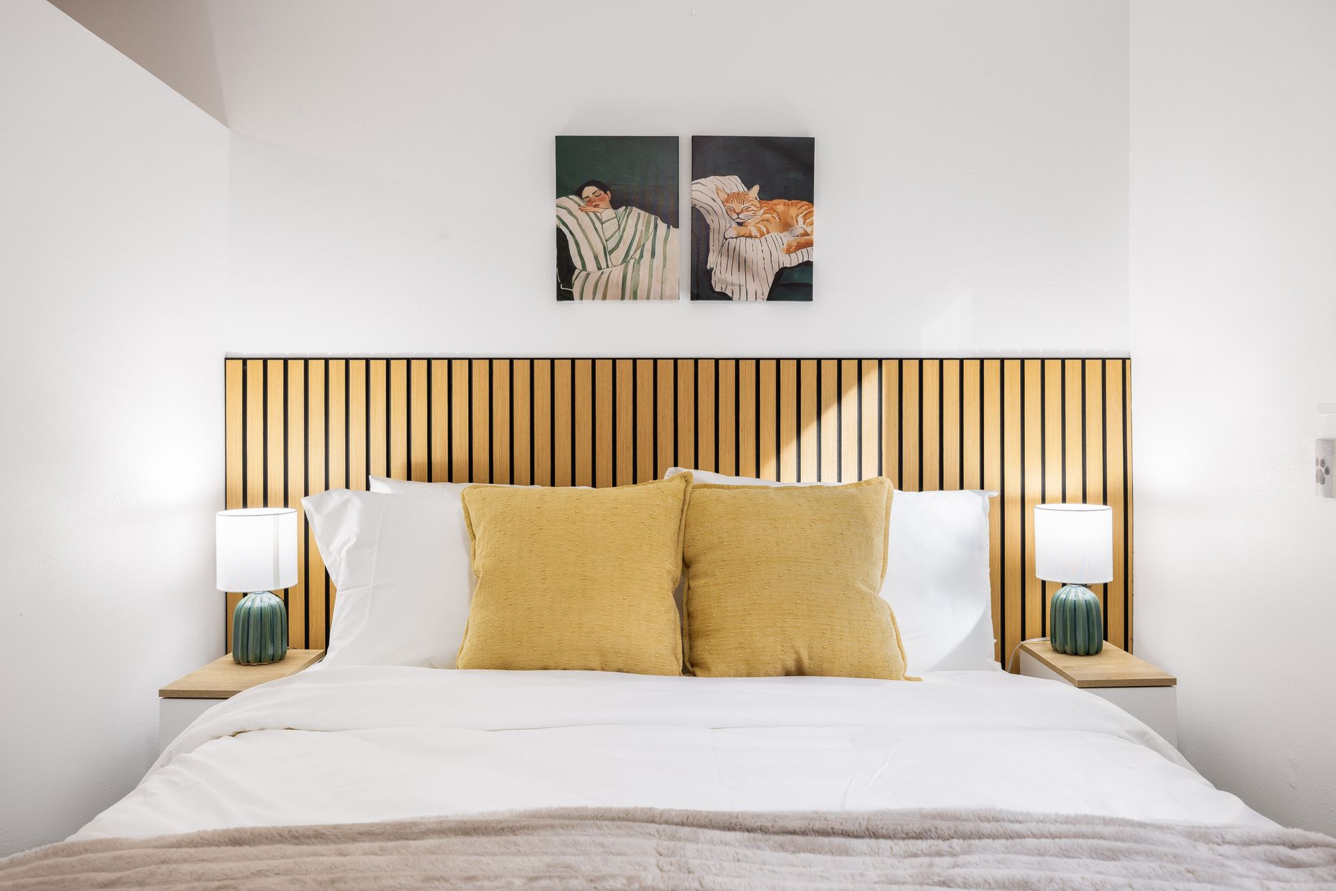Bright bedroom with a wooden slatted headboard, white bedding, and mustard yellow pillows.