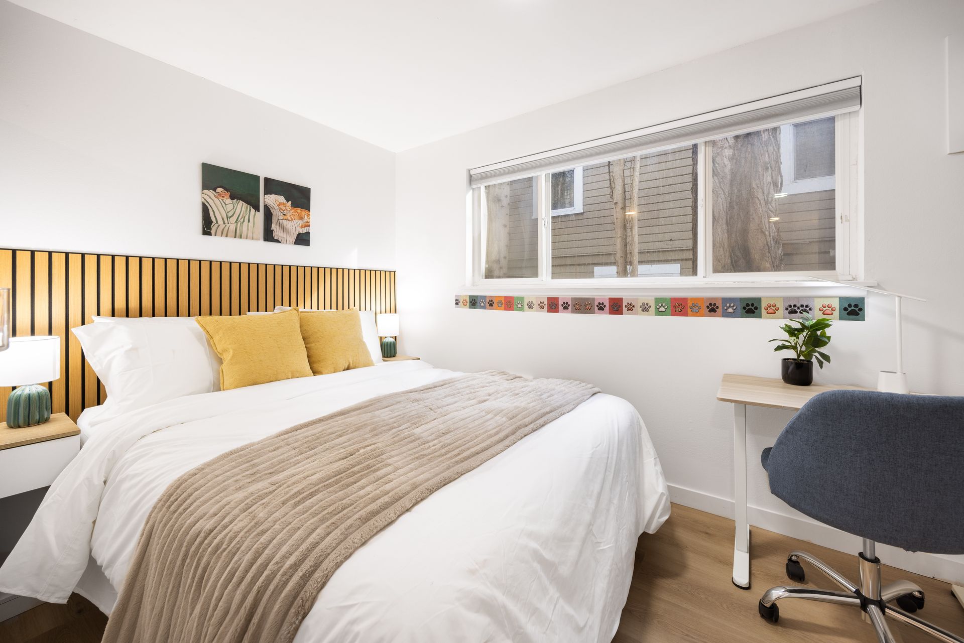 Bright bedroom with a bed, desk, window, and gray chair in a clean, modern interior