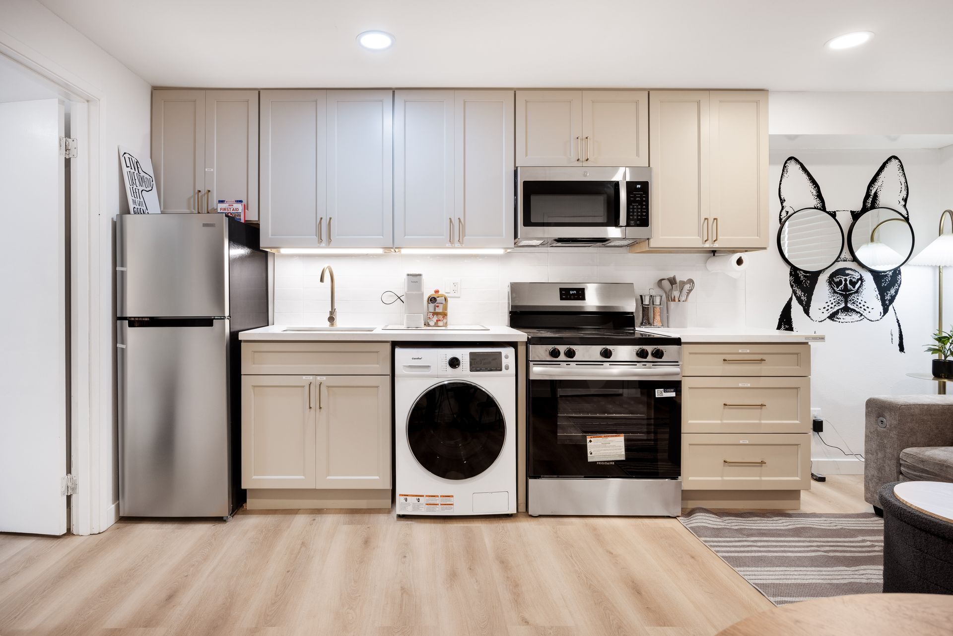 Modern kitchen with stainless steel appliances, white cabinets, and a washer under the counter