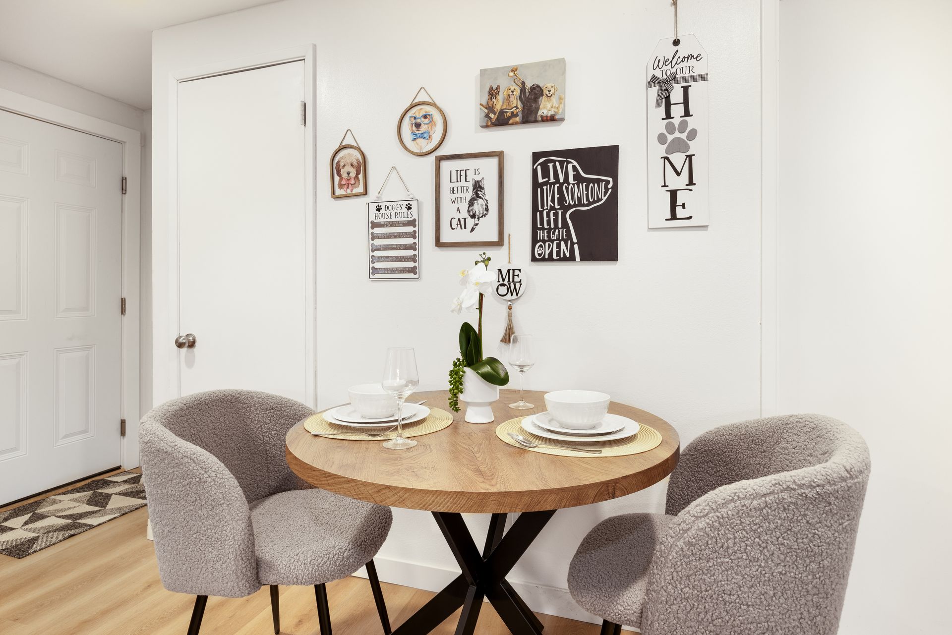 Cozy dining nook with round wood table, gray chairs, and wall art in a bright white room