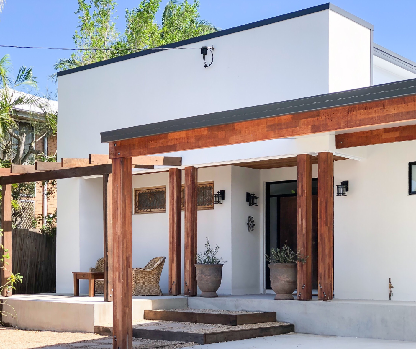 Modern white house exterior with wooden porch posts and steps in bright sunlight