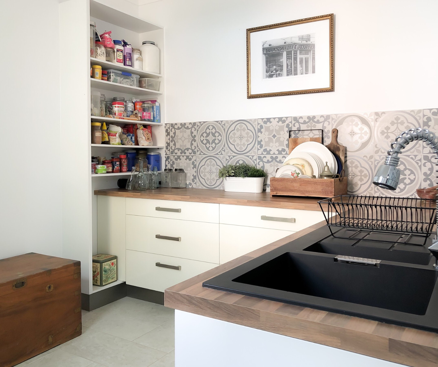Modern kitchen with black sink, wooden countertop, open pantry shelves, and patterned tile backsplash