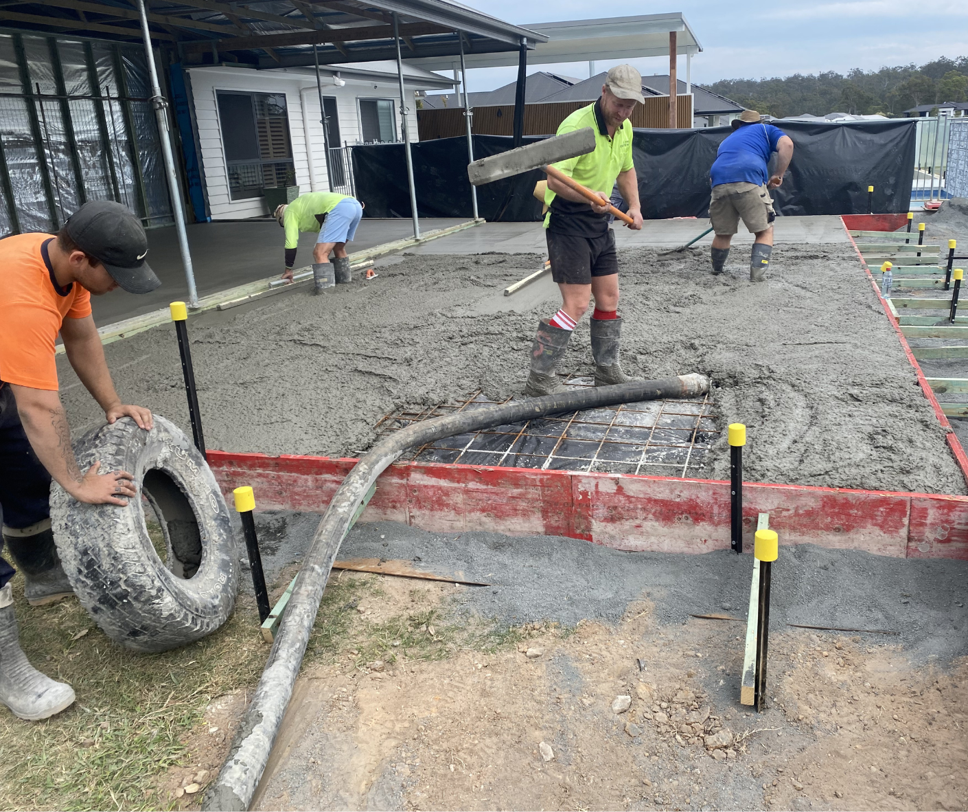 Construction crew pouring and leveling wet concrete in an outdoor foundation area. Construction crew pouring and leveling wet concrete in an outdoor foundation area.