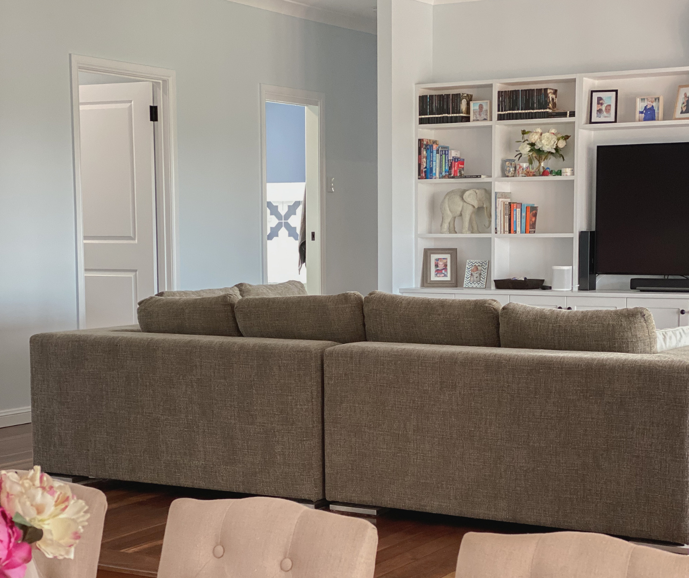 Living room with gray sectional sofa, white built-in shelves, and TV on the right