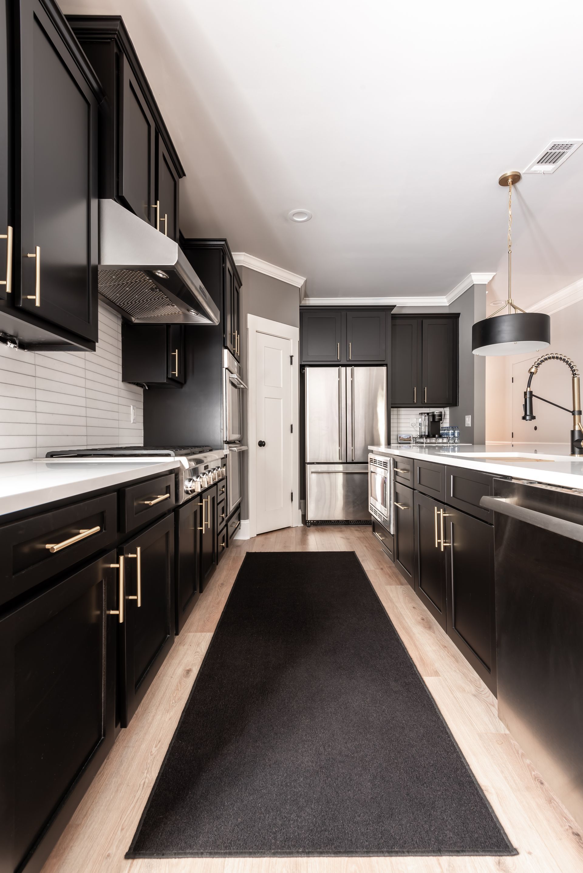 Modern black-and-white galley kitchen with stainless steel appliances and a long dark runner rug