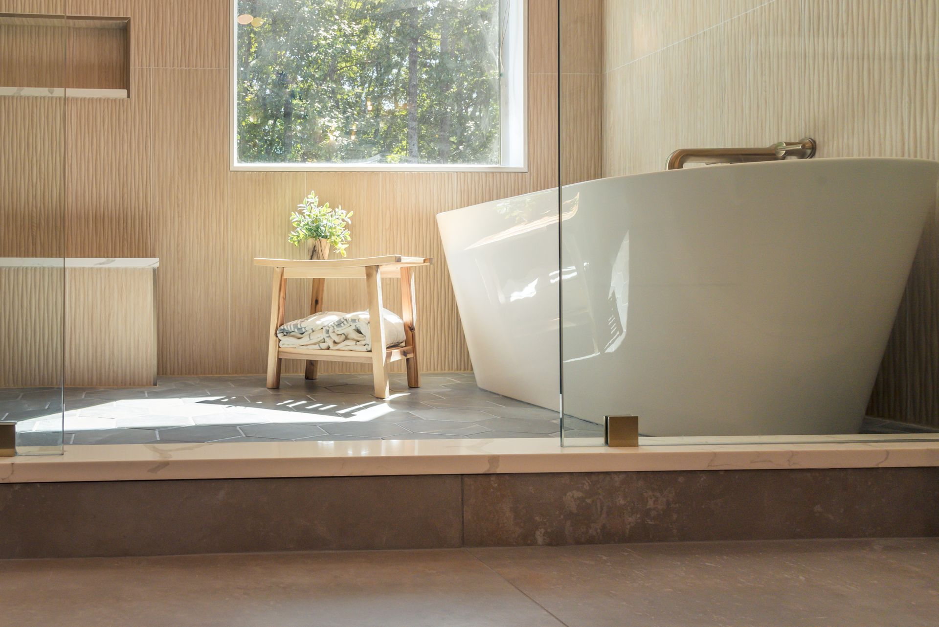 Modern bathroom with a freestanding white bathtub, wood paneling, and a small stool by the window
