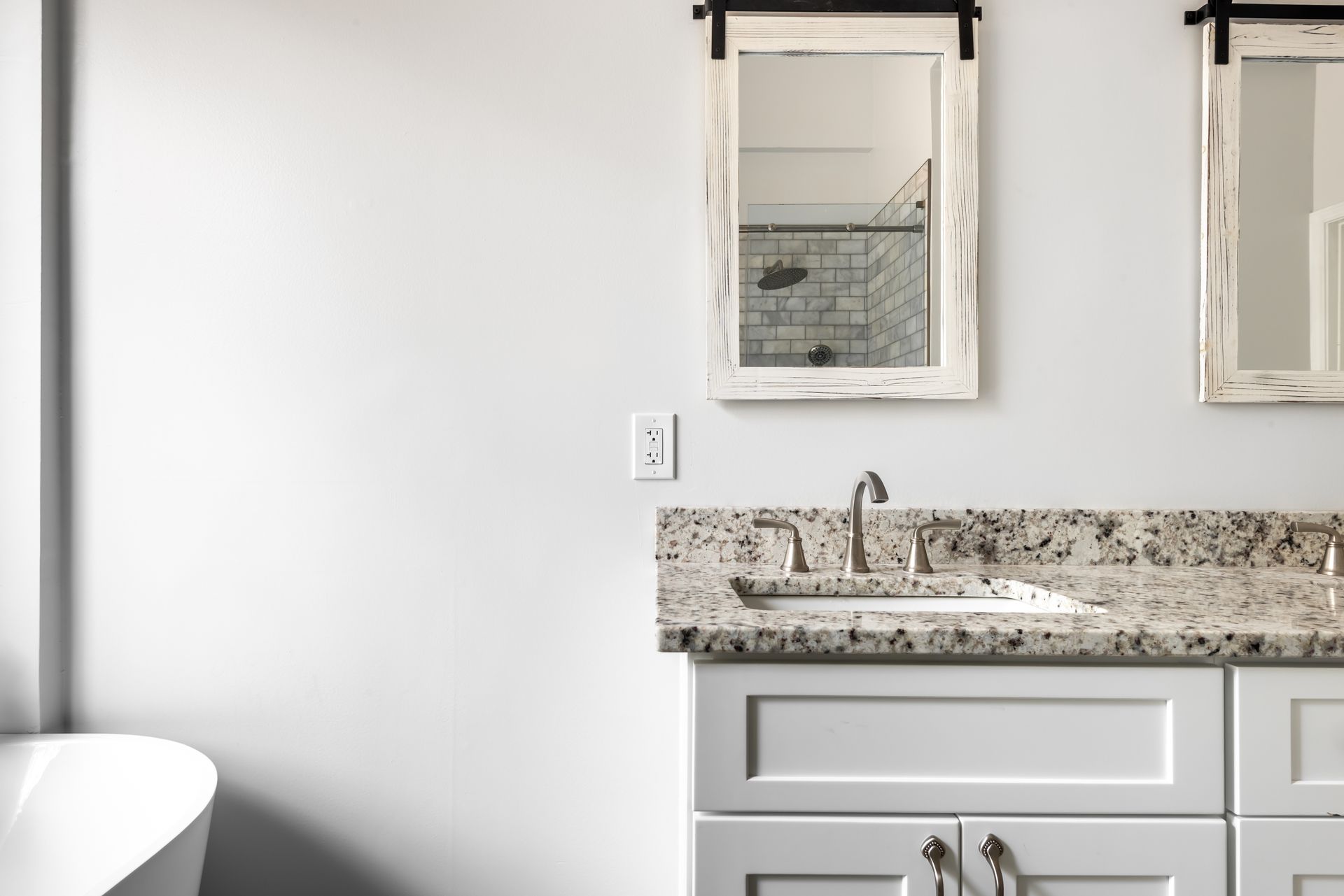 Bright bathroom vanity with granite countertop, sink, mirror, and white walls