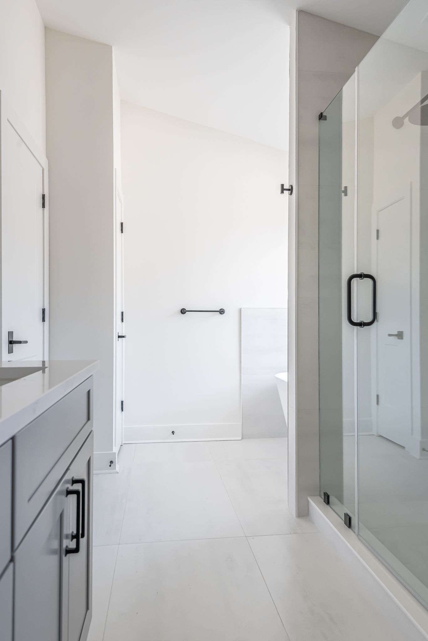 Bright white bathroom with glass shower, vanity, and towel bar.