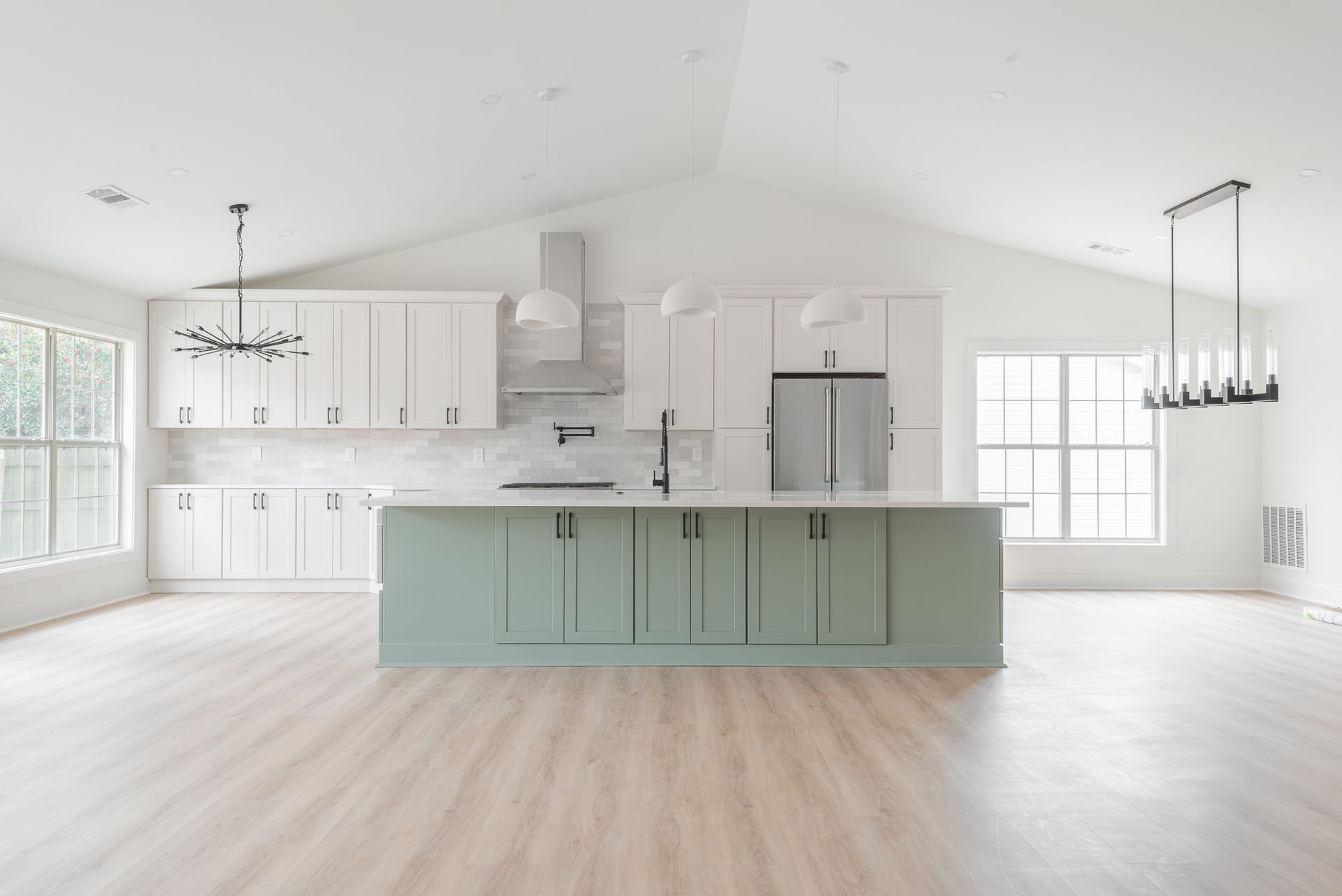 Bright modern kitchen with mint island, white cabinets, stainless appliances, and open floor plan