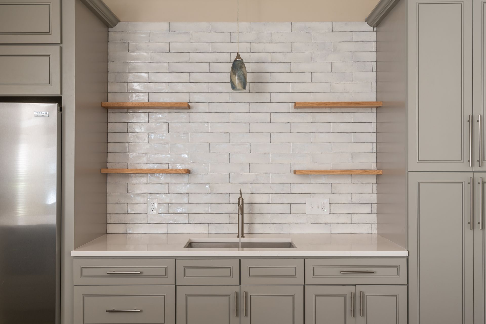 Modern kitchen nook with white subway tile backsplash, wood shelves, and built-in cabinets and sink