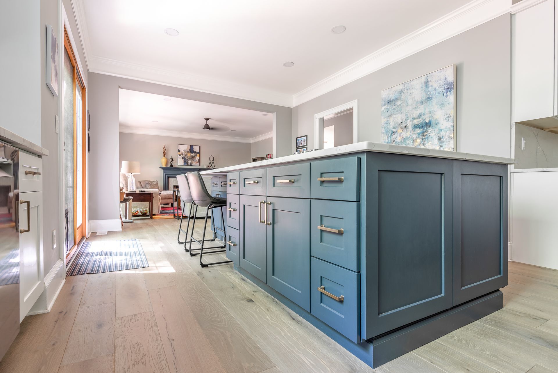 Bright kitchen with blue island cabinets, white walls, and bar stools in a modern open-plan home
