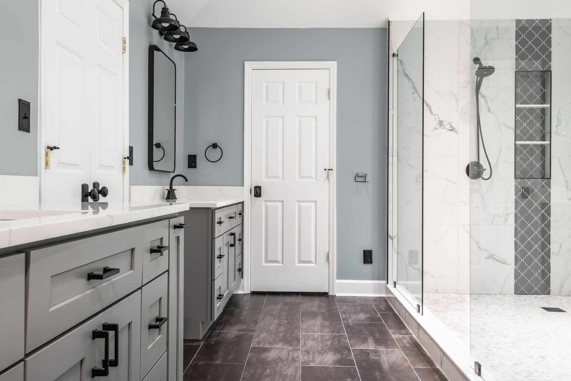 Modern bathroom with gray vanity, large mirror, white shower, and dark tile floor