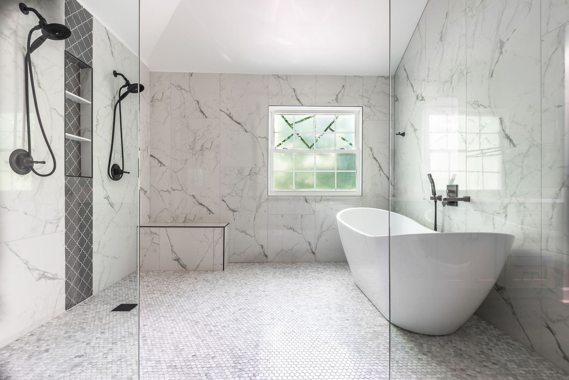 Modern white marble bathroom with glass shower, freestanding tub, and small window