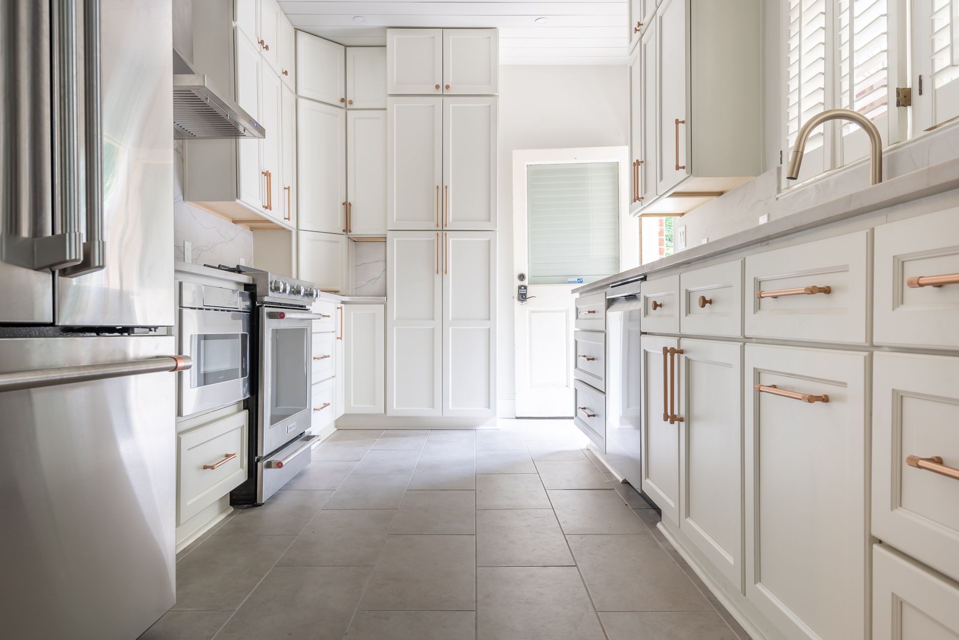 Bright white galley kitchen with stainless steel appliances and gold-accented cabinets