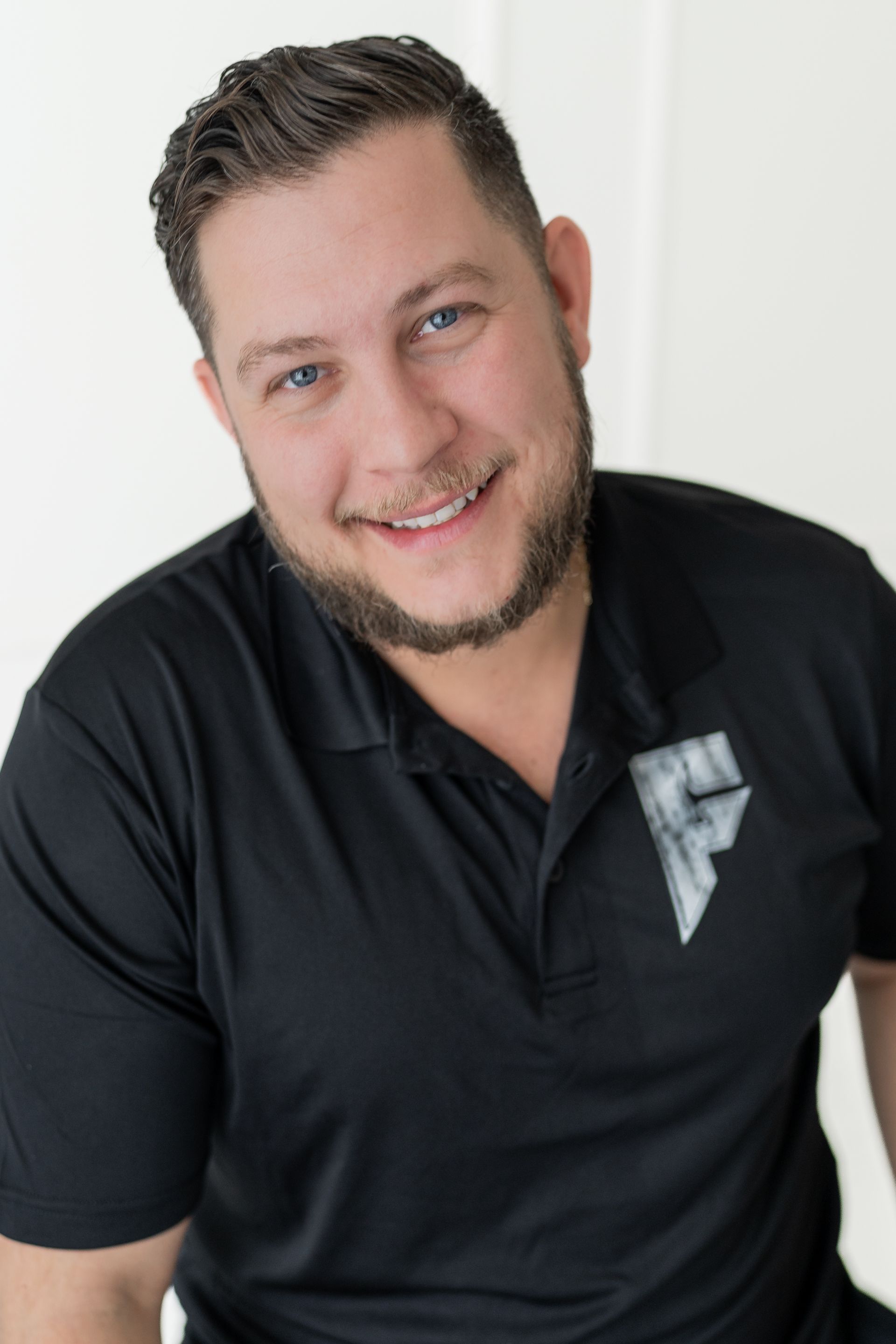 Smiling man in a black polo shirt against a light background
