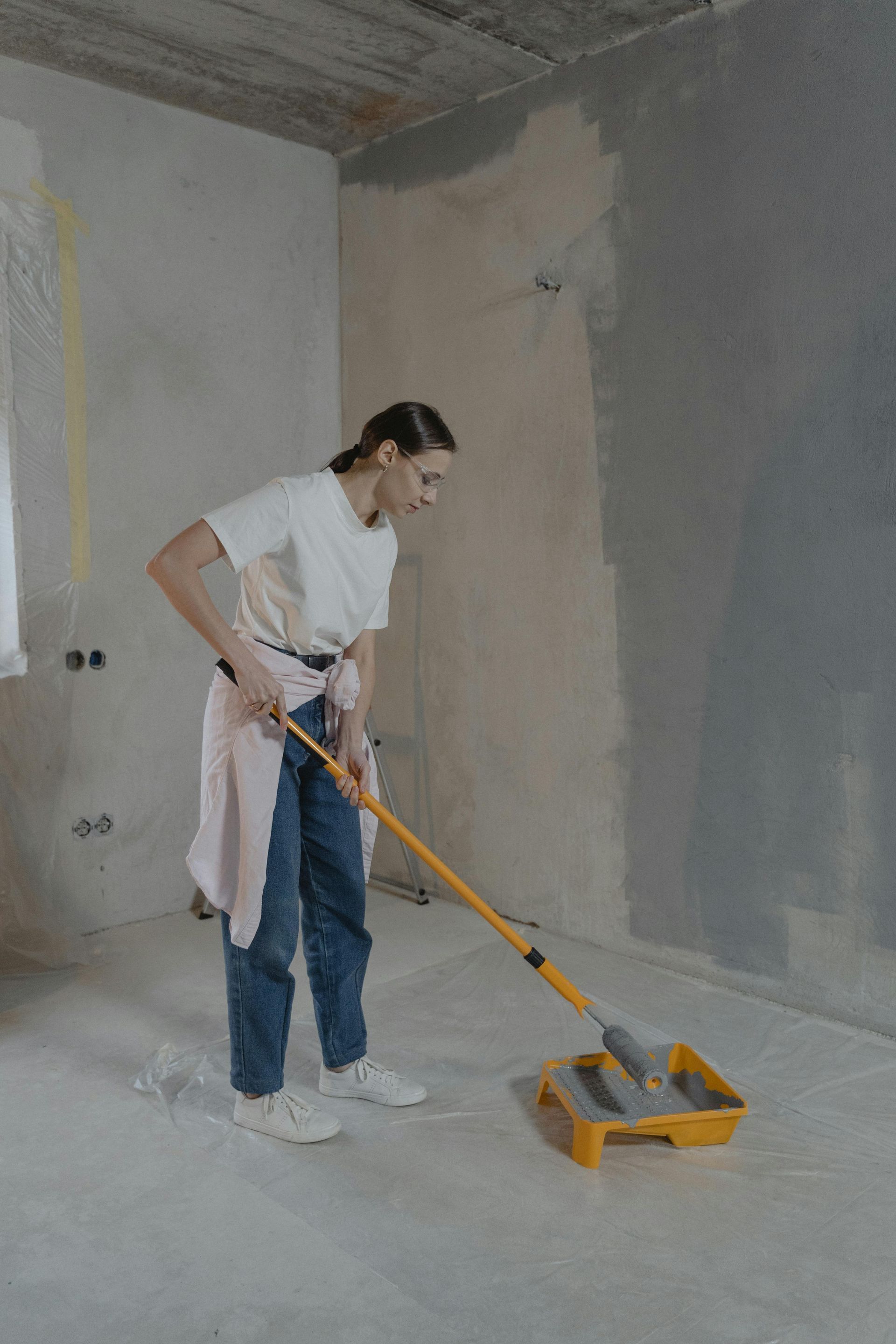 Person mopping a bare room floor with a yellow cleaning tool