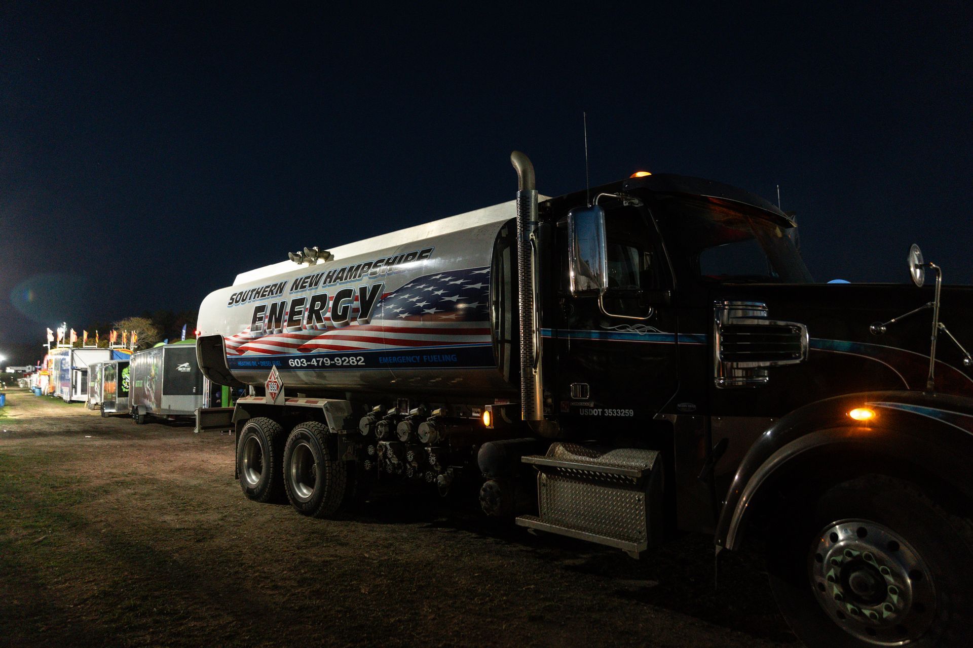 Fuel truck at night with the American flag design, parked near other vehicles.
