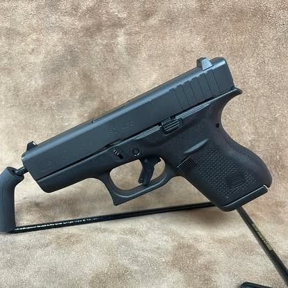 Black handgun on a display stand against a brown background.