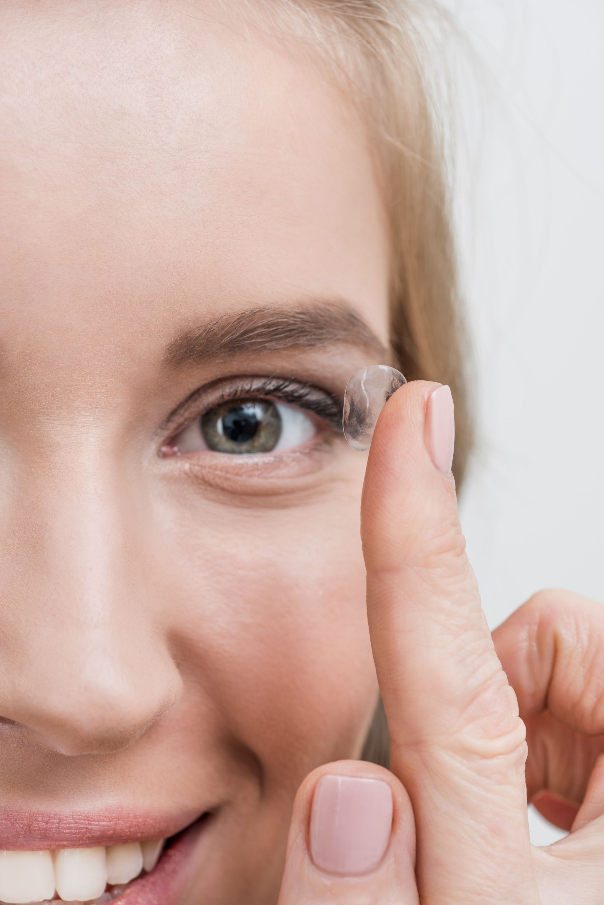 close up of young smiling woman with contact lens