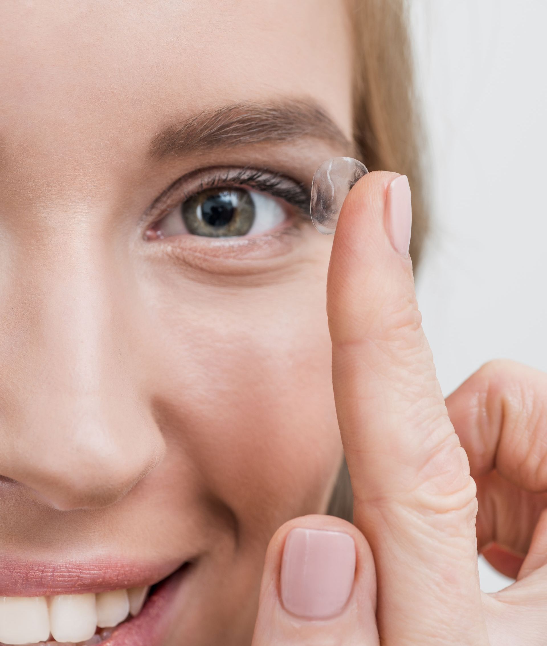 close up of young smiling woman with contact lens