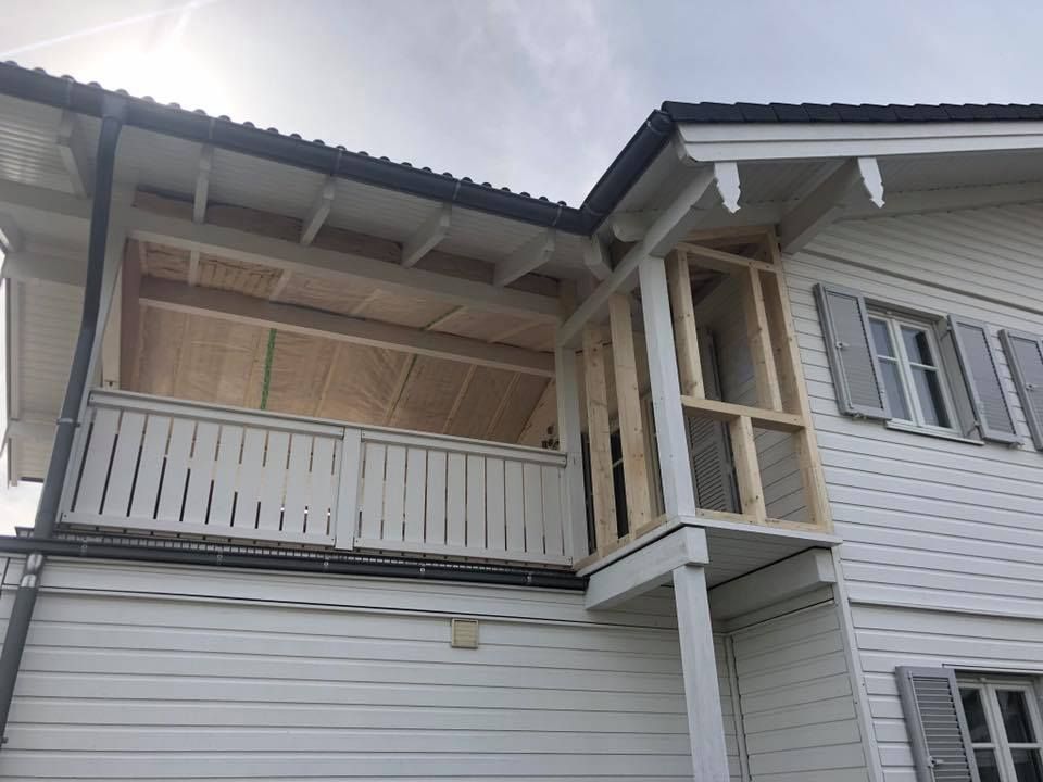 Une maison blanche avec un balcon sur le côté.