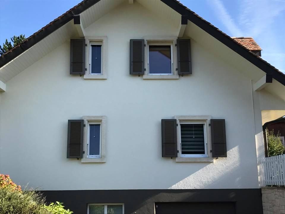 Une maison blanche avec des volets marron aux fenêtres
