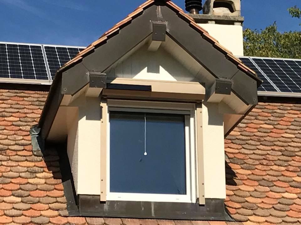 Un toit avec une fenêtre et des panneaux solaires dessus réalisé par la société Laurent/Carvalho Sàrl